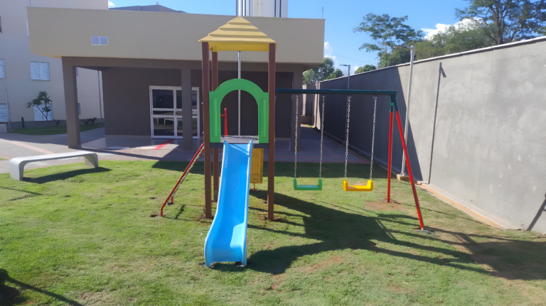 Playground infantil com escorregador azul e balanços instalado em área externa de condomínio residencial